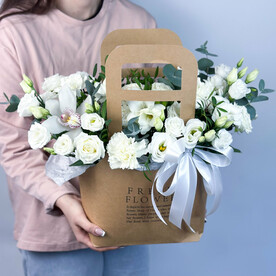 Нежная белая композиция в сумочке из кустовых роз, лизиантусов, фрезий и диантусов