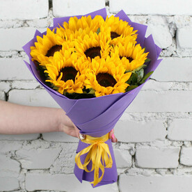Букет 7 подсолнухов с зеленью в фиолетовой упаковке